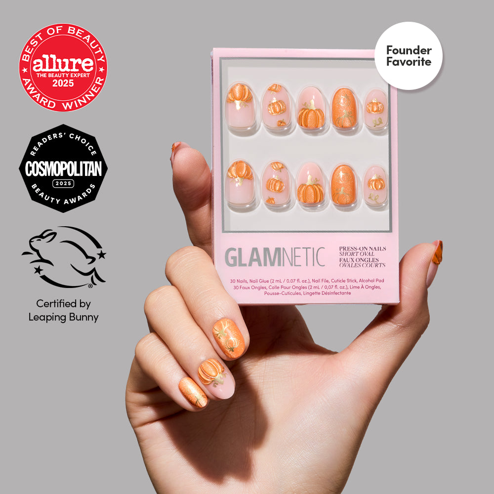 A hand holds a box of glamnetic Golden Gourds press-on nails featuring short oval nails with peach and gold designs. The background is gray, and the image highlights beauty award badges along with the Leaping Bunny cruelty-free certification. - Product image