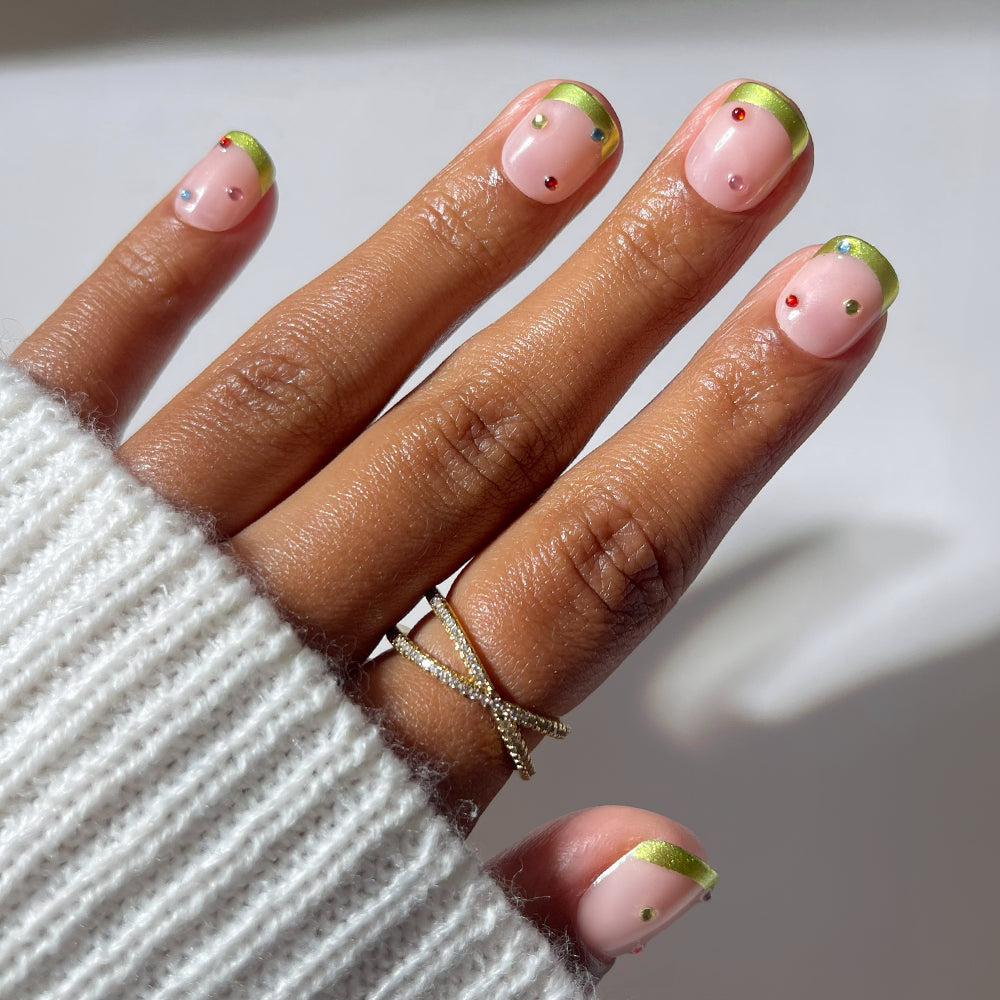 Glamnetic Goodie Gumdrops short, light pink vegan press-on nails featuring metallic green chrome French tips and small, colorful jewel accents.