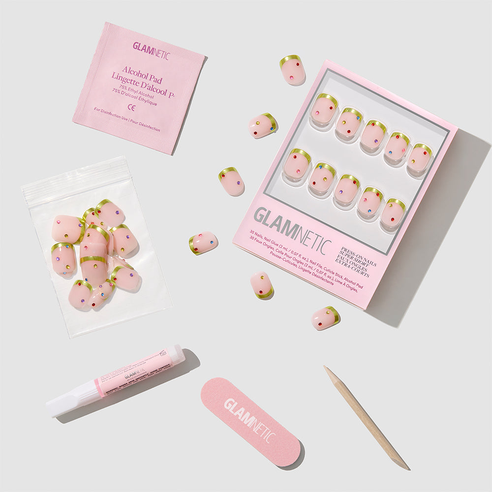 Glamnetic Goodie Gumdrops vegan press-on nails featuring a nude base with pink chrome French tips and small colorful dots, including an alcohol pad, nail file, nail glue, and a wooden cuticle stick. - Product image