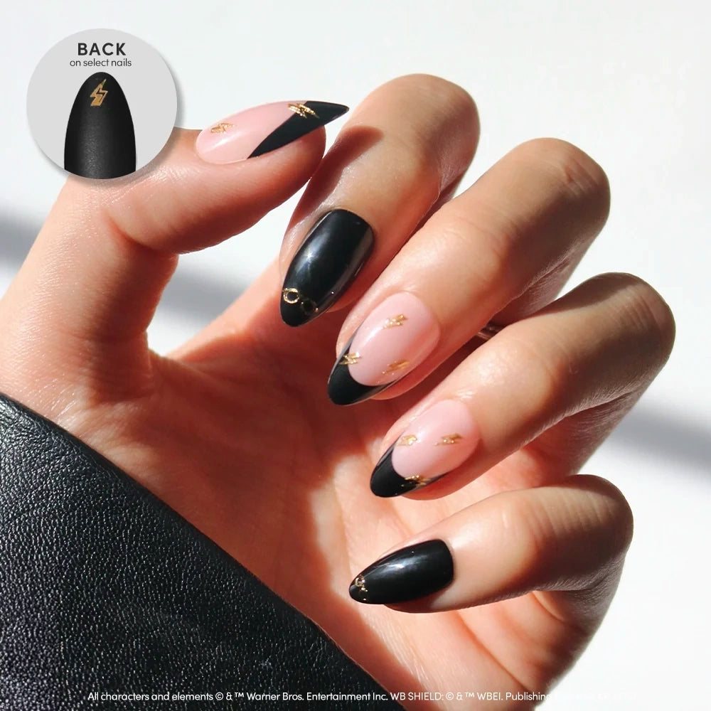 Almond-shaped Harry Potter™ press-on nails featuring black and light pink French tips, accented with small gold lightning bolt and round glasses charms.