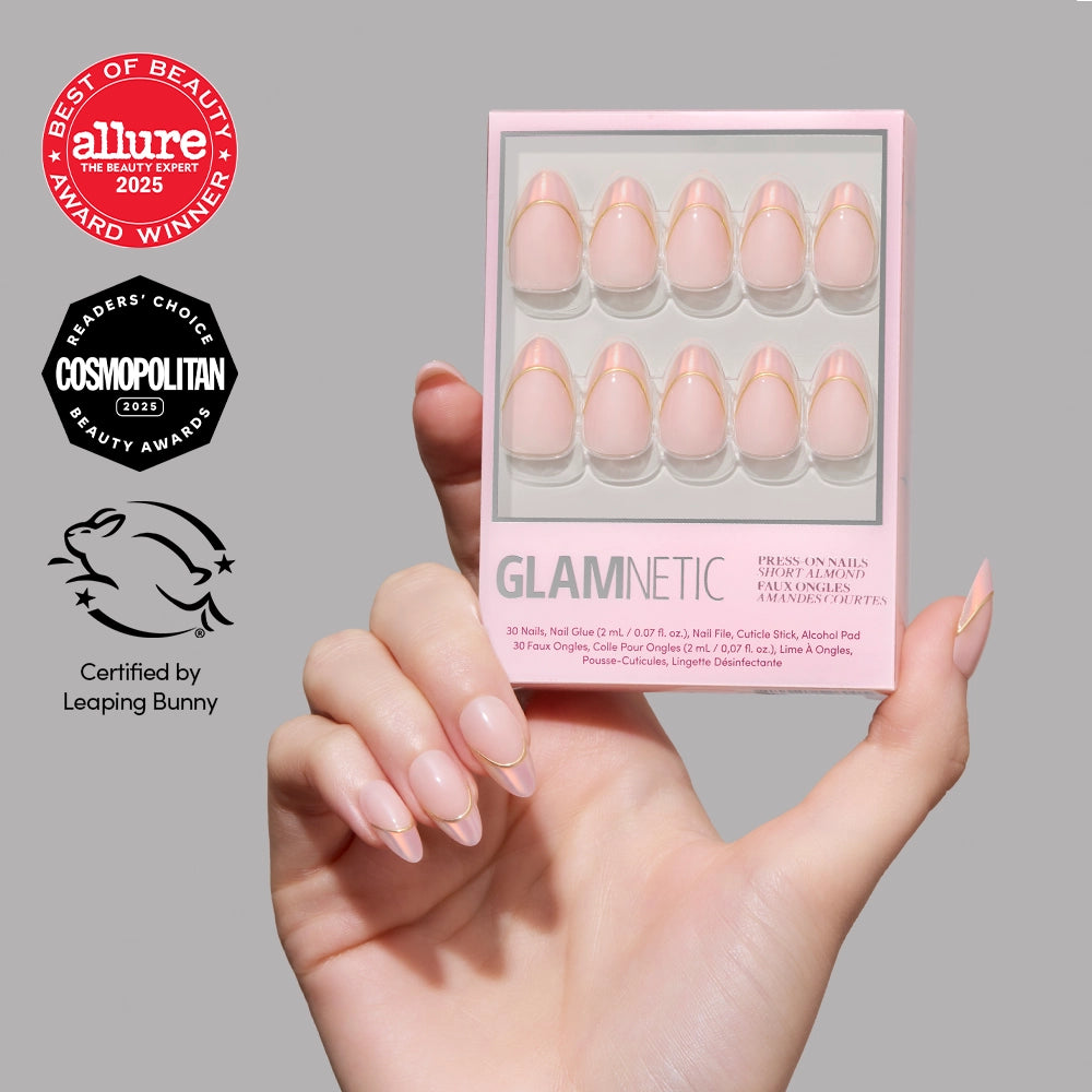 A hand with glossy, natural-looking short almond nails holds a box of glamnetic Heavenly Touch press-on nails. Beauty award logos and a Leaping Bunny cruelty-free certification appear on the left. - Product image