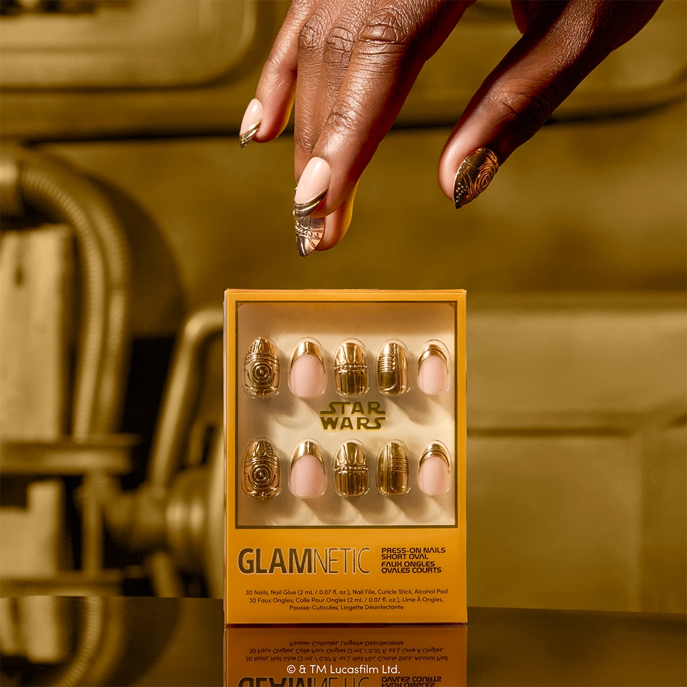 Help! I Think I’m Melting! - A hand with gold and pink press-on nails holds a box of glamnetic Help! I Think I’m Melting! press-on nails. The packaging showcases striking gold foil press-on nails, with the official glamnetic branding prominently displayed.