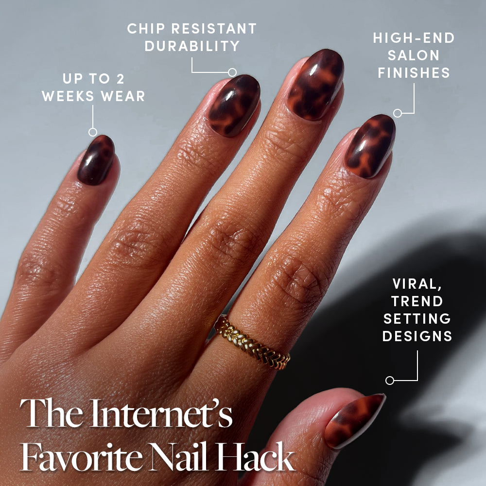 A hand wears glamnetic’s High Society short oval press-on nails in a brown and black tortoiseshell design. Text features up to 2 weeks’ chip-resistant, salon-quality wear and viral trends. One finger is accessorized with a gold ring. - Product image