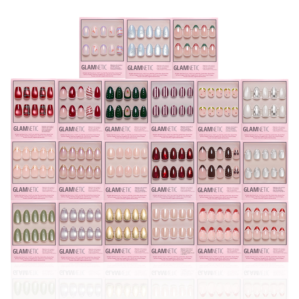 A display of 20 glamnetic Holiday In The City salon-quality manicure press-on nail sets in various colors and designs, arranged in a neat grid pattern with pink packaging and clear front panels showcasing the nails. - Product image