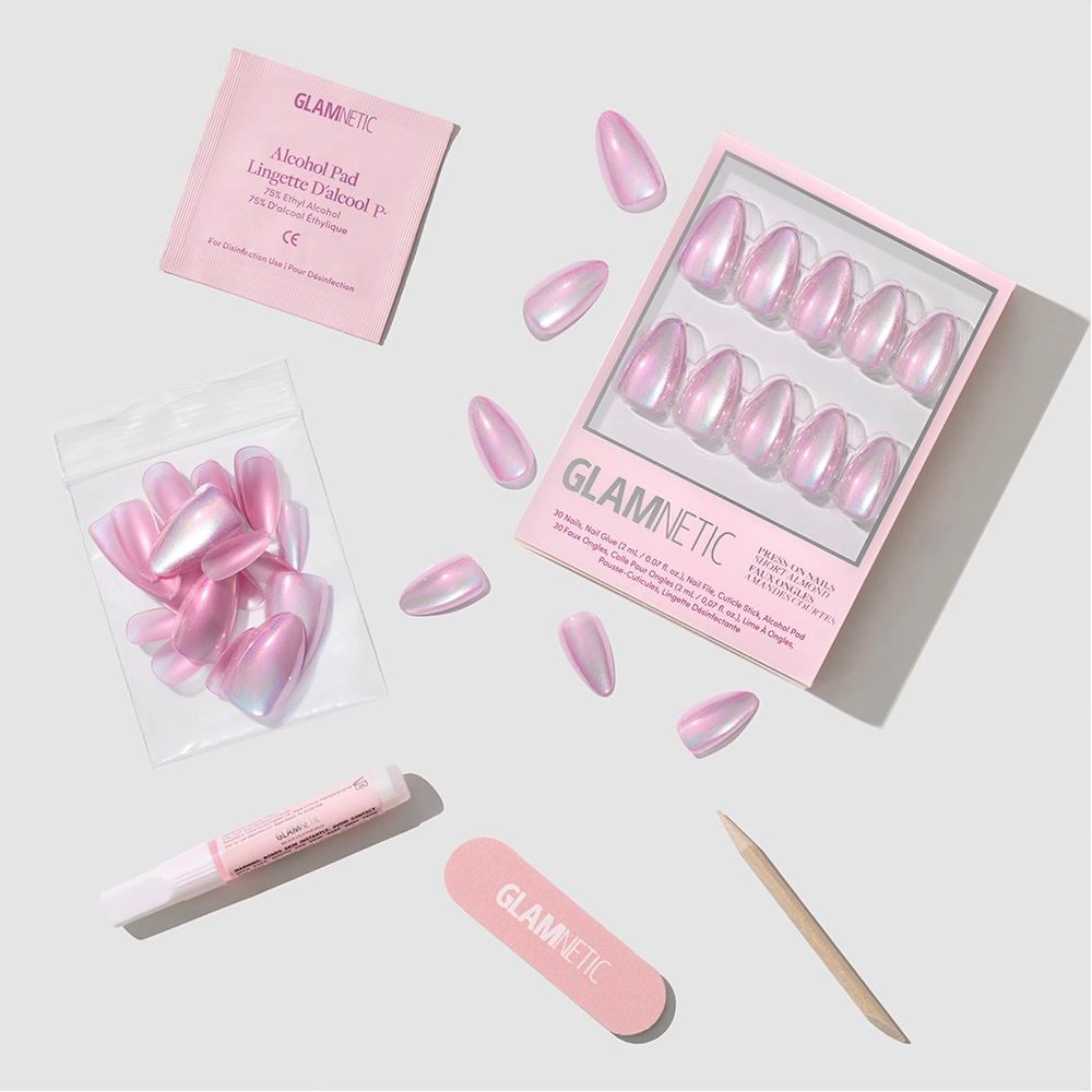 The glamnetic Iconic Oyster Press-On Nails in short almond shape feature a pearlescent velvet finish and come with a nail file, cuticle stick, nail glue, alcohol pad, and extra nails—arranged neatly on a light surface.