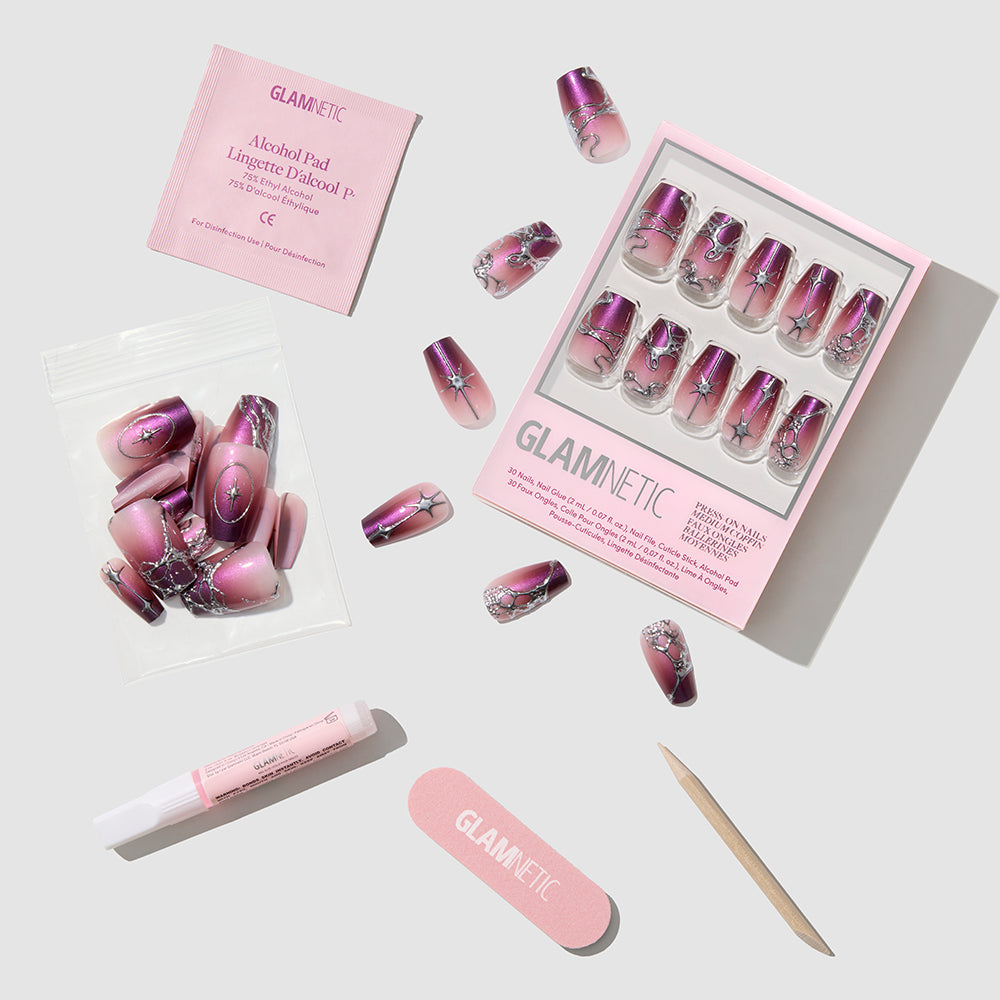 The Immortal Kiss press-on nails set by glamnetic, featuring pink and purple glossy ombre coffin nails, along with glue, a nail file, a wooden cuticle stick, an alcohol pad, and extra nails, is neatly arranged on a white background. - Product image
