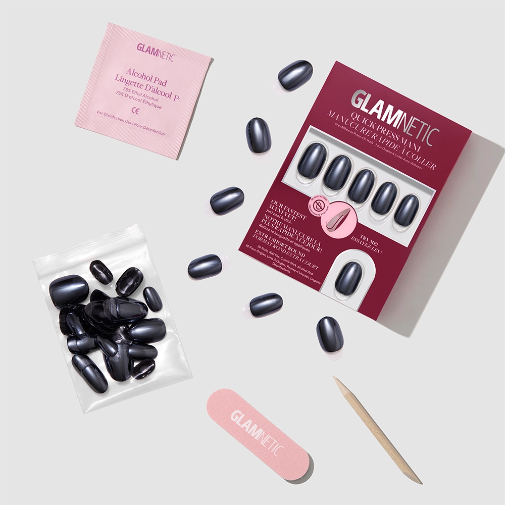 The glamnetic Ink Spell set features black stick-on nails along with accessories—a nail file, alcohol pad, wooden cuticle stick, and extra nails—neatly arranged on a light background. - Product image