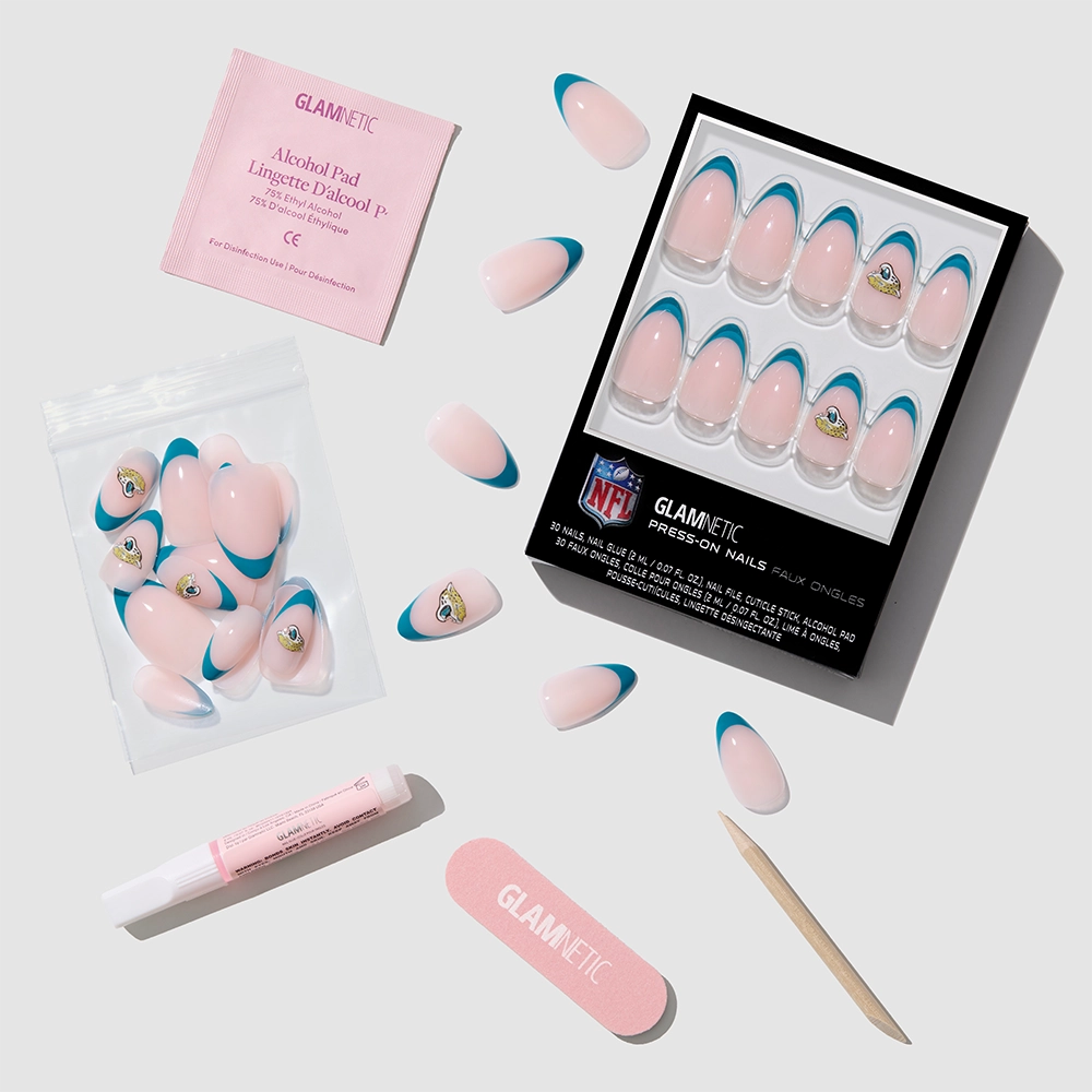 The glamnetic Jacksonville Jaguars Press-On Nail Set comes in pink and blue with NFL logo accents. It includes an alcohol pad, nail glue, buffer, cuticle stick, and extra almond manis—all shown on a light gray background. - Product image