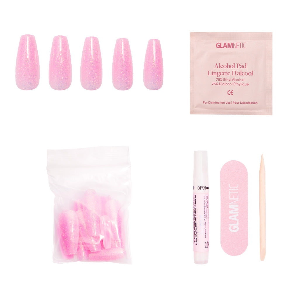 The Juicy press-on nails kit by glamnetic features glossy pink, coffin-shaped nails for Y2K vibes. Includes alcohol pad, pink nail bag, glue tube, pink file, and wooden cuticle stick—all arranged on a white background. - Product image