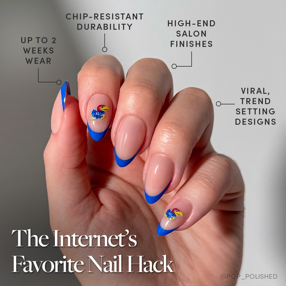 A hand with long, almond-shaped nails sports the Kansas Jayhawks Press-On Nail Set by glamnetic, featuring a nude base, bold blue French tips, and colorful abstract accents—durable, trendy, and perfect for fans. - Product image
