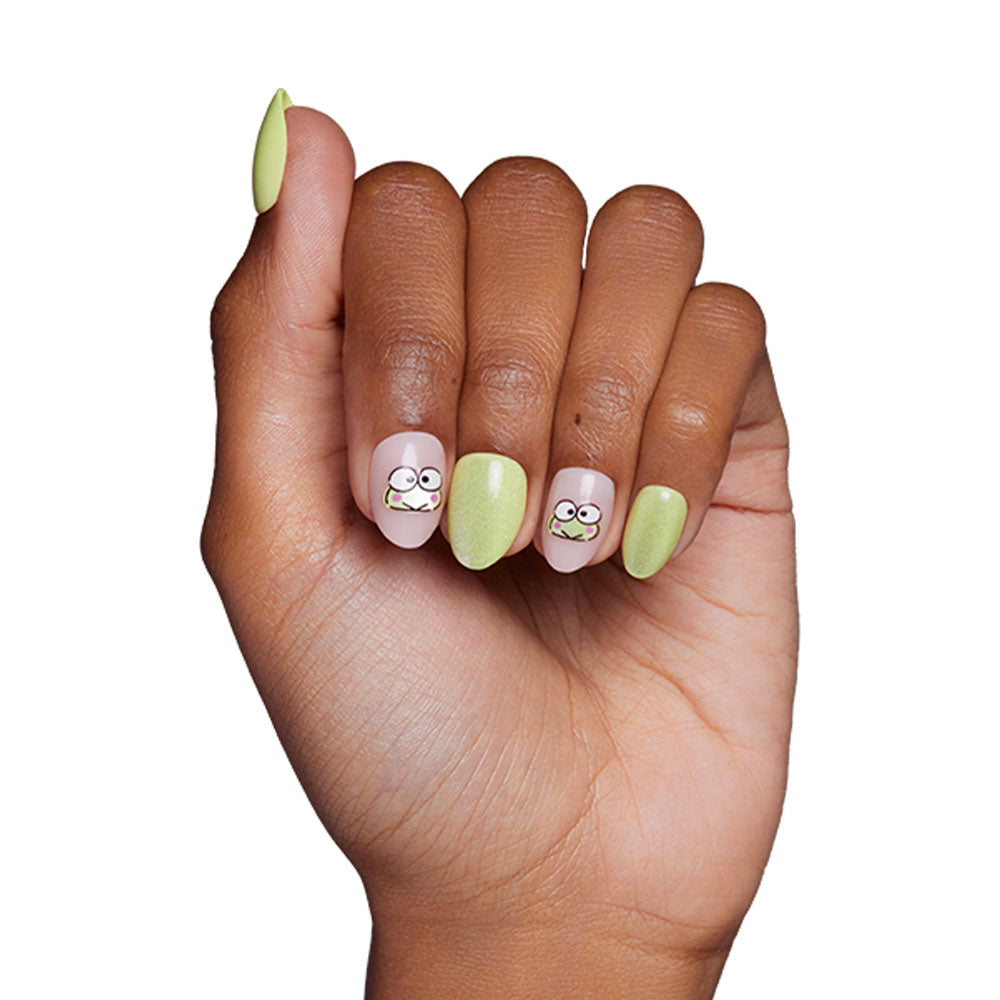 A hand with light green glamnetic Keroppi™ nails on the thumb, index, and pinky; the middle and ring nails show cartoon frog faces. The background is white. These reusable nails make it easy to switch up your style. - Product image