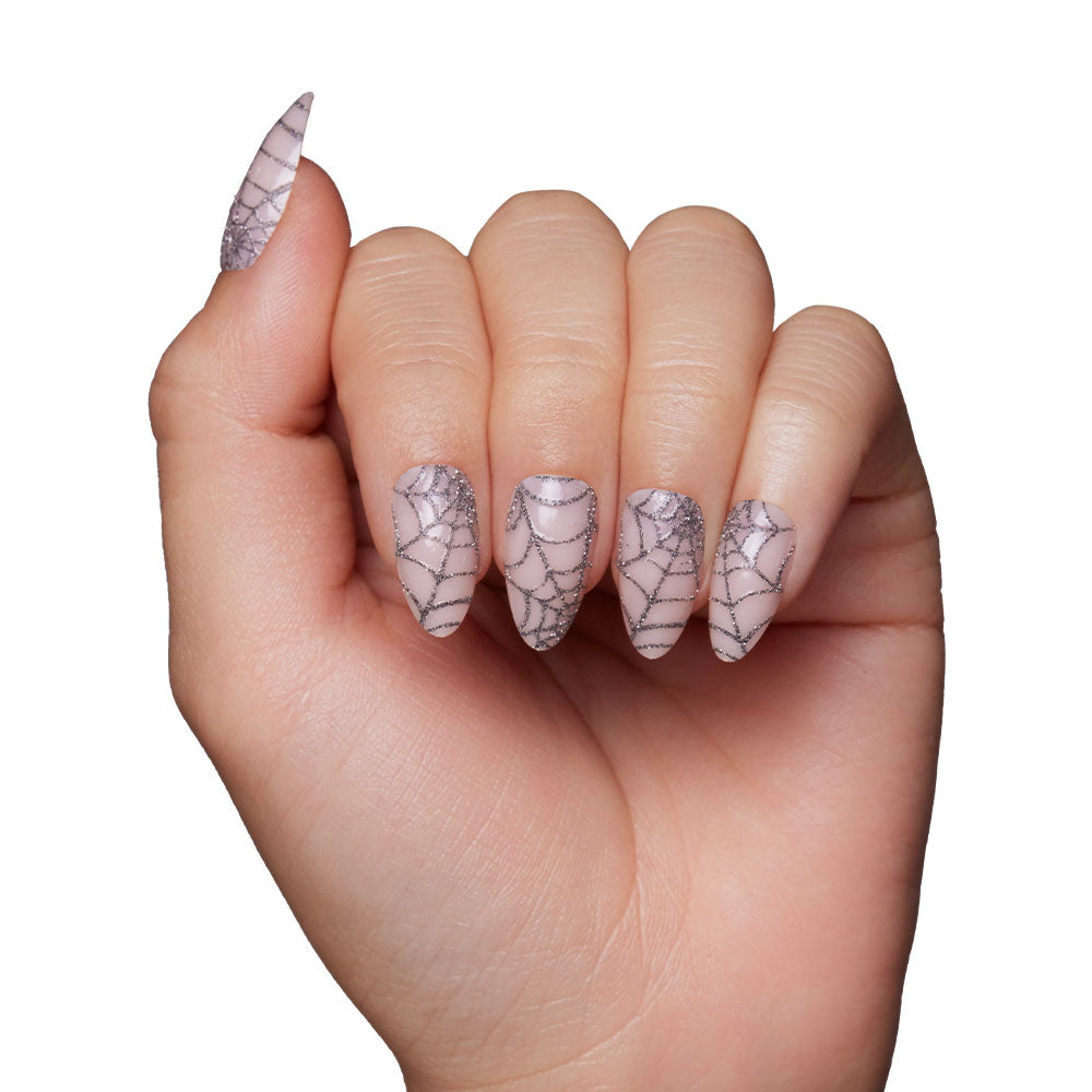 A hand with long, almond-shaped nails in glamnetic’s Lady Web set—silver base and black sparkly spiderwebs—shown on a white background, perfect for Halloween. - Product image