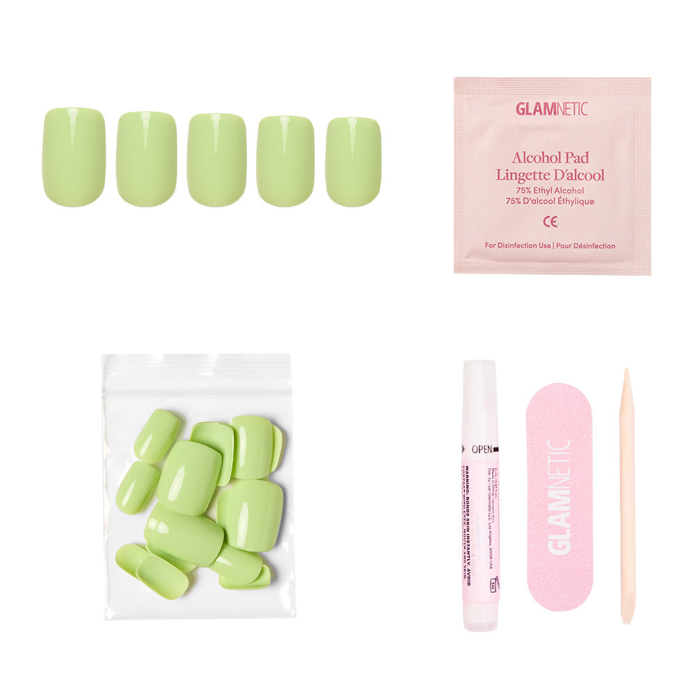 The glamnetic Light Sage Nail Set includes glossy short squoval nails, an alcohol pad, extra green nails in a clear pouch, nail glue, a pink nail file, and a wooden cuticle stick—displayed on a white background. - Product image