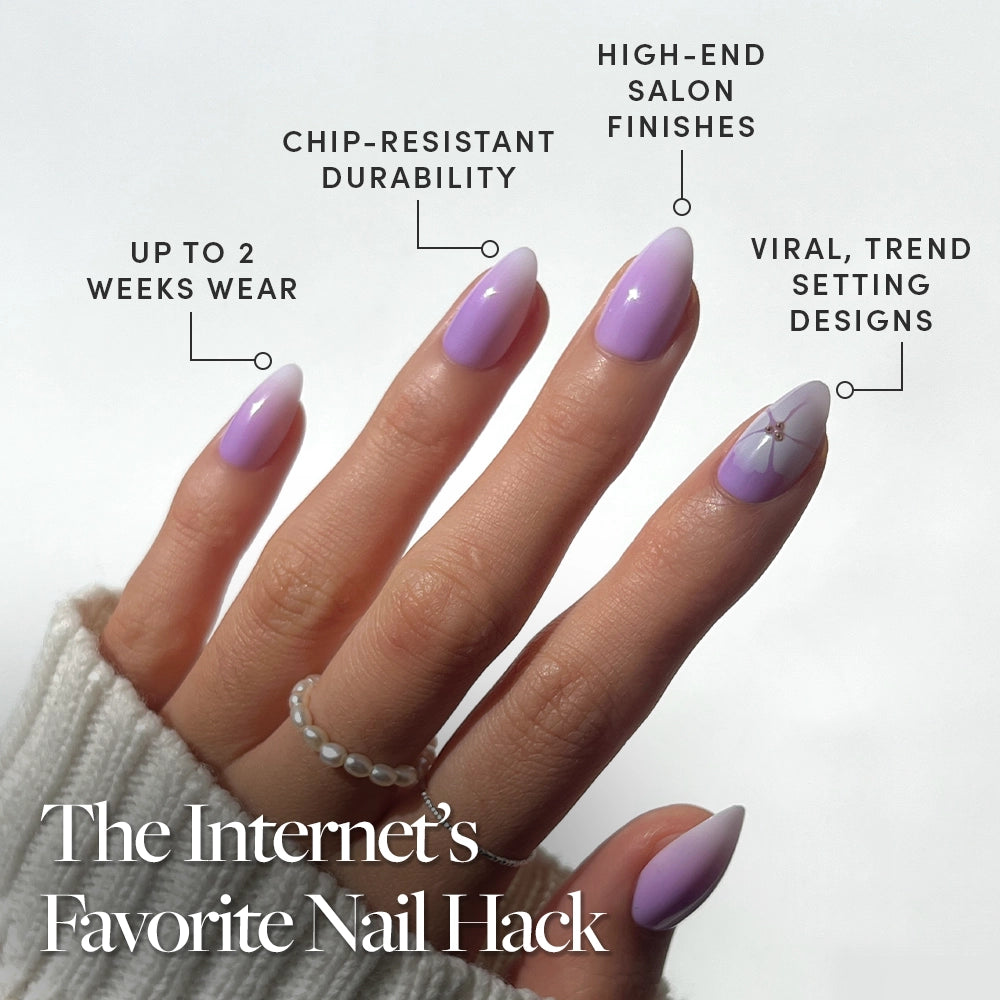 A hand shows off glamnetics Lilac Reef: long, almond nails in a glossy lavender ombré with a white design and a floral accent. Enjoy trendy styles, lasting durability, and wear for up to two weeks. - Product image