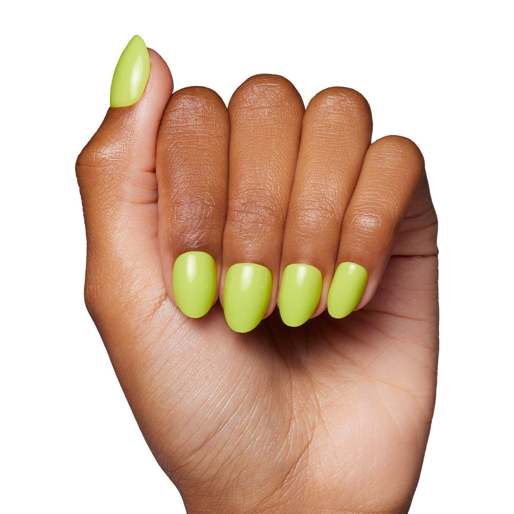 A hand with medium brown skin displays neatly manicured, short oval nails painted in Lime Green by glamnetic. The glossy lime shade stands out against the clean white background. - Product image