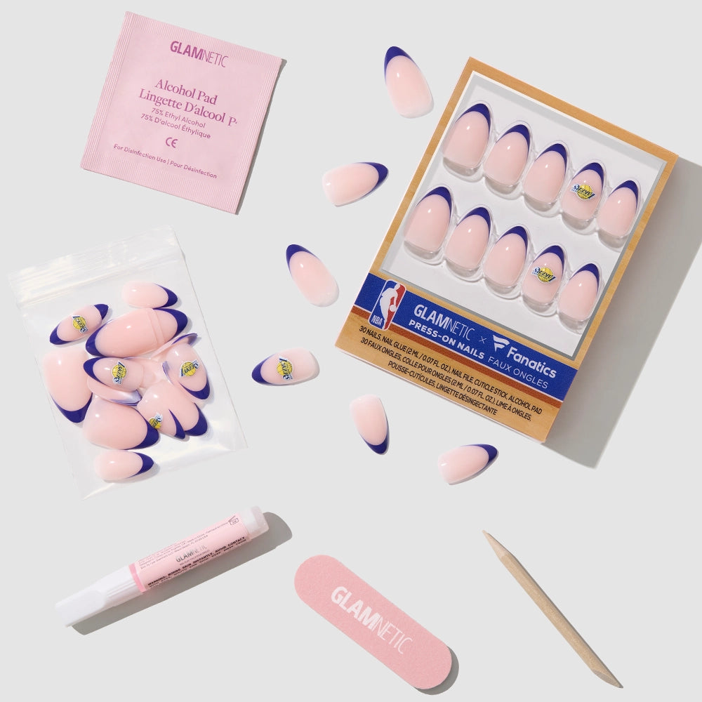 The Los Angeles Lakers Press-On Nail Set by glamnetic features pink press-on nails with purple French tips in an almond shape, a nail file, cuticle stick, nail glue, alcohol pad, and extra nails on a light gray surface for a salon look. - Product image