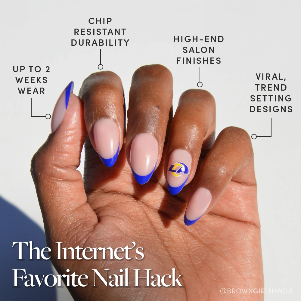 A hand wears glamnetic’s Los Angeles Rams Press-On Nail Set: almond-shaped press-ons with a nude base, bright blue tips, and a yellow-purple Rams logo. Enjoy salon finishes, long wear, chip resistance, and trendy fan designs. - Product image