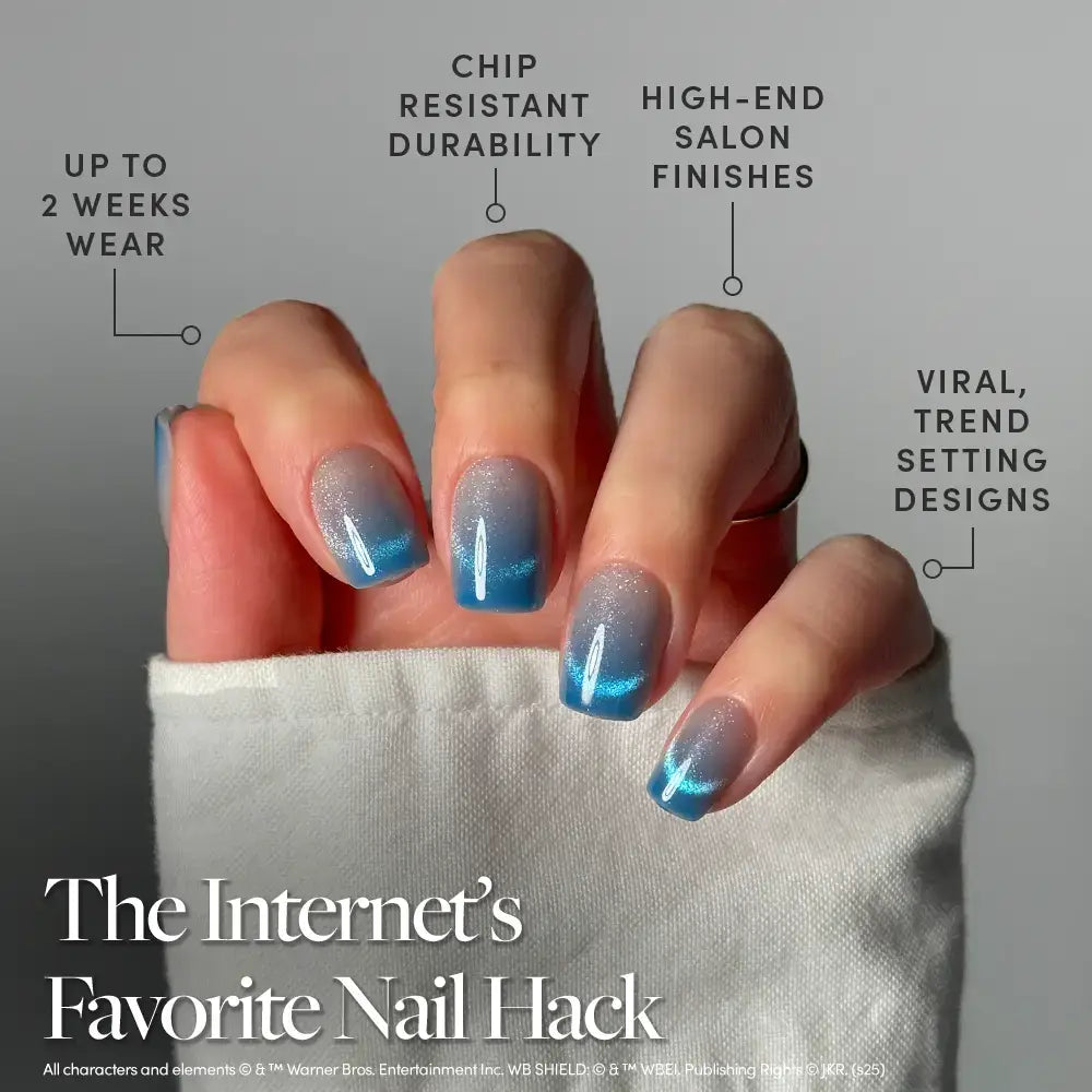 A hand with glossy blue ombre nails is shown, featuring the Lumos velvet blue gradient press-ons by glamnetic for a luxurious touch. Text highlights features like up to 2 weeks of wear, chip-resistant durability, high-end finishes, and trendy designs. These glamnetic press-on nails offer shiny nail art with a sleek, modern look. - Product image