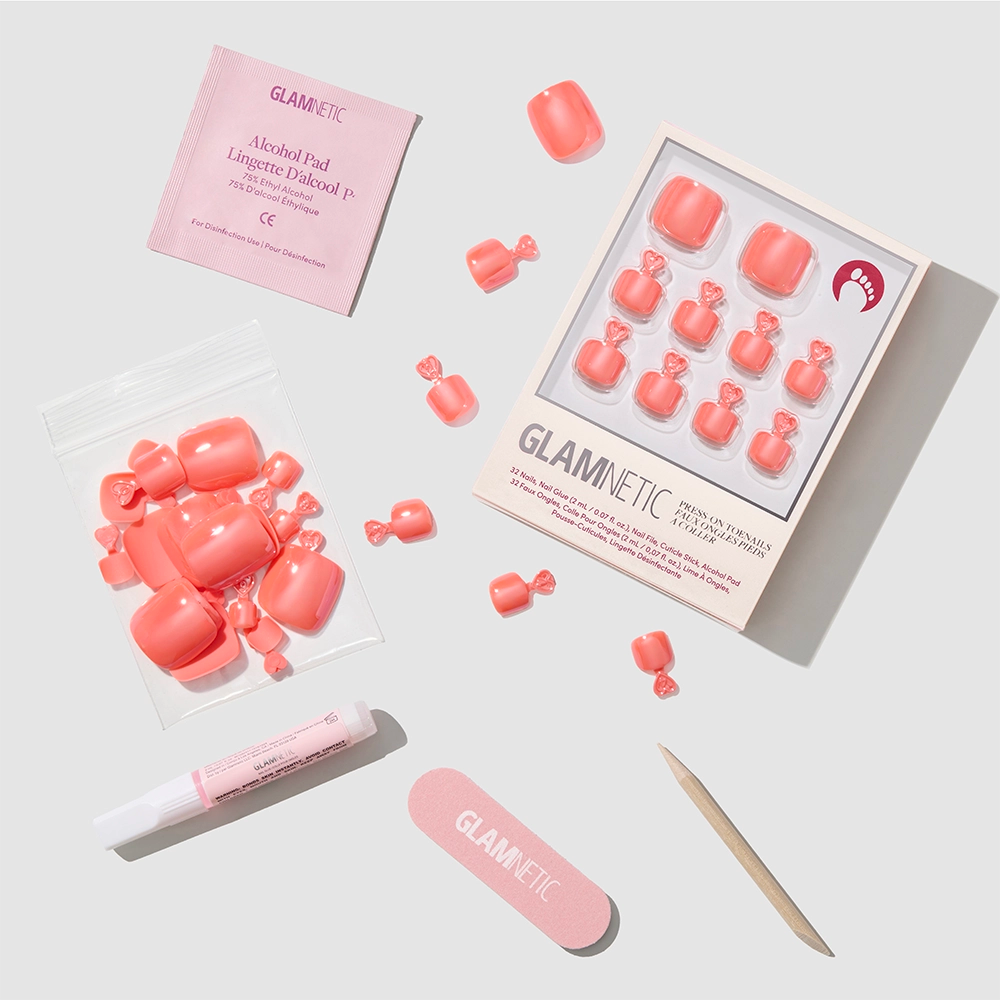 The glamnetic Lush Coral Toenail set features glazed vegan press-on toenails, adhesive tabs, nail file, cuticle stick, alcohol pad, and nail glue—everything you need for an easy DIY pedi—arranged on a light gray background. - Product image