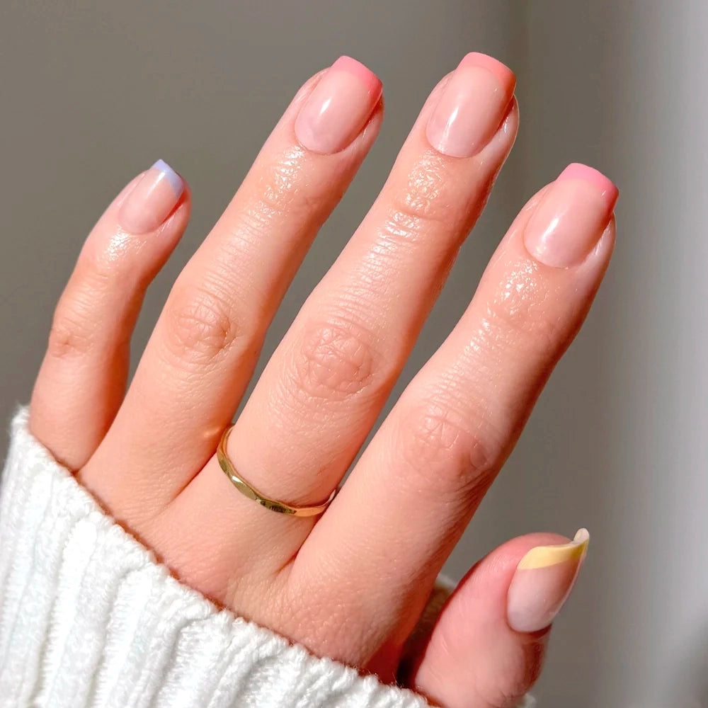 A hand with short squoval Macarons nails featuring colorful pastel French tips.