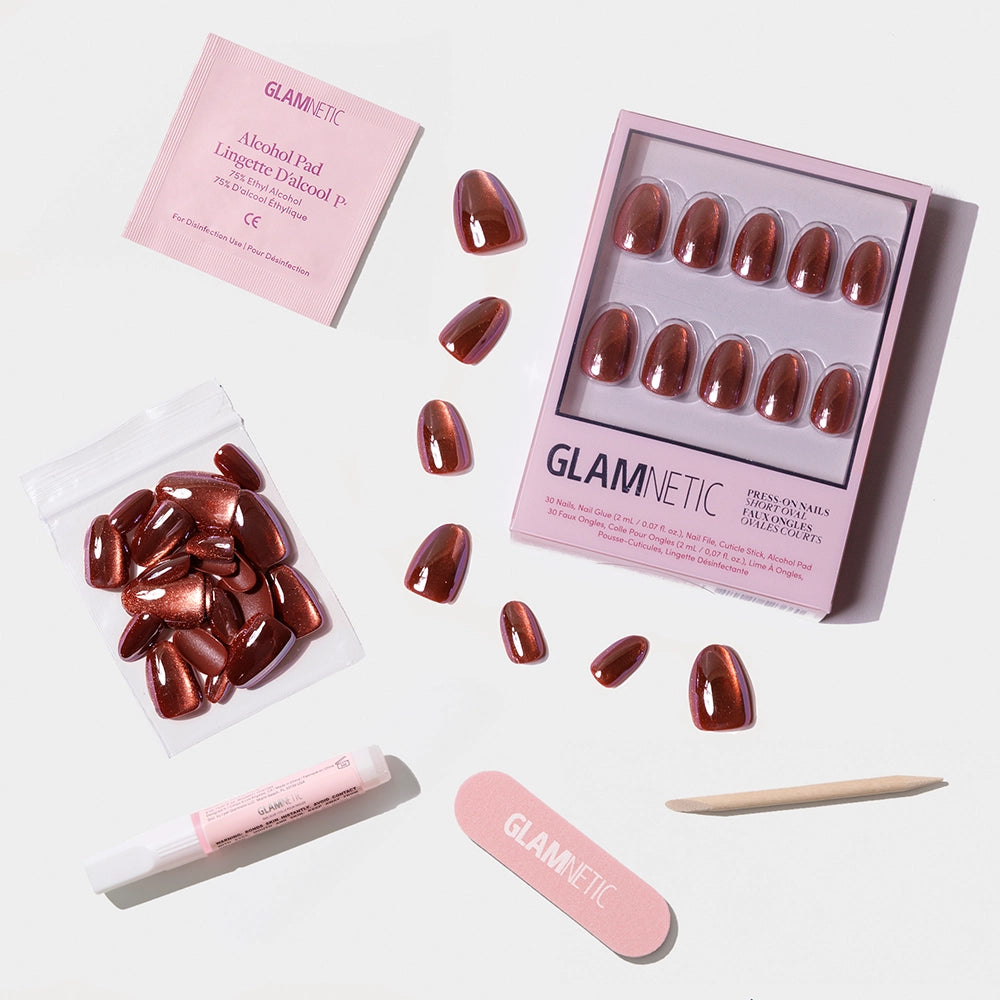 The Magnetic Moscow press-on nails by glamnetic, in metallic reddish-brown short ovals, are shown on a white background with extra nails, cuticle stick, nail glue, nail file, and an alcohol pad. - Product image