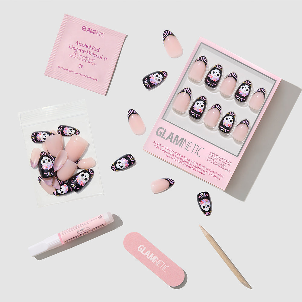 Introducing the glamnetic Mani De Los Muertos press-on nail set, showcasing playful pink and Kuromi-themed short almond nails. Each set comes with an alcohol pad, nail file, cuticle stick, glue, and extra nails—all displayed on a light gray background. This festive collection is perfect for those who enjoy fun styles and trendy looks inspired by Day of the Dead nails. - Product image