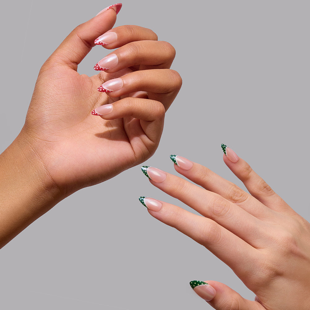 Two hands displaying short almond glamnetic Matching PJs press-on nails featuring a French tip design with red and green polka dots for a festive holiday mani. - Product image