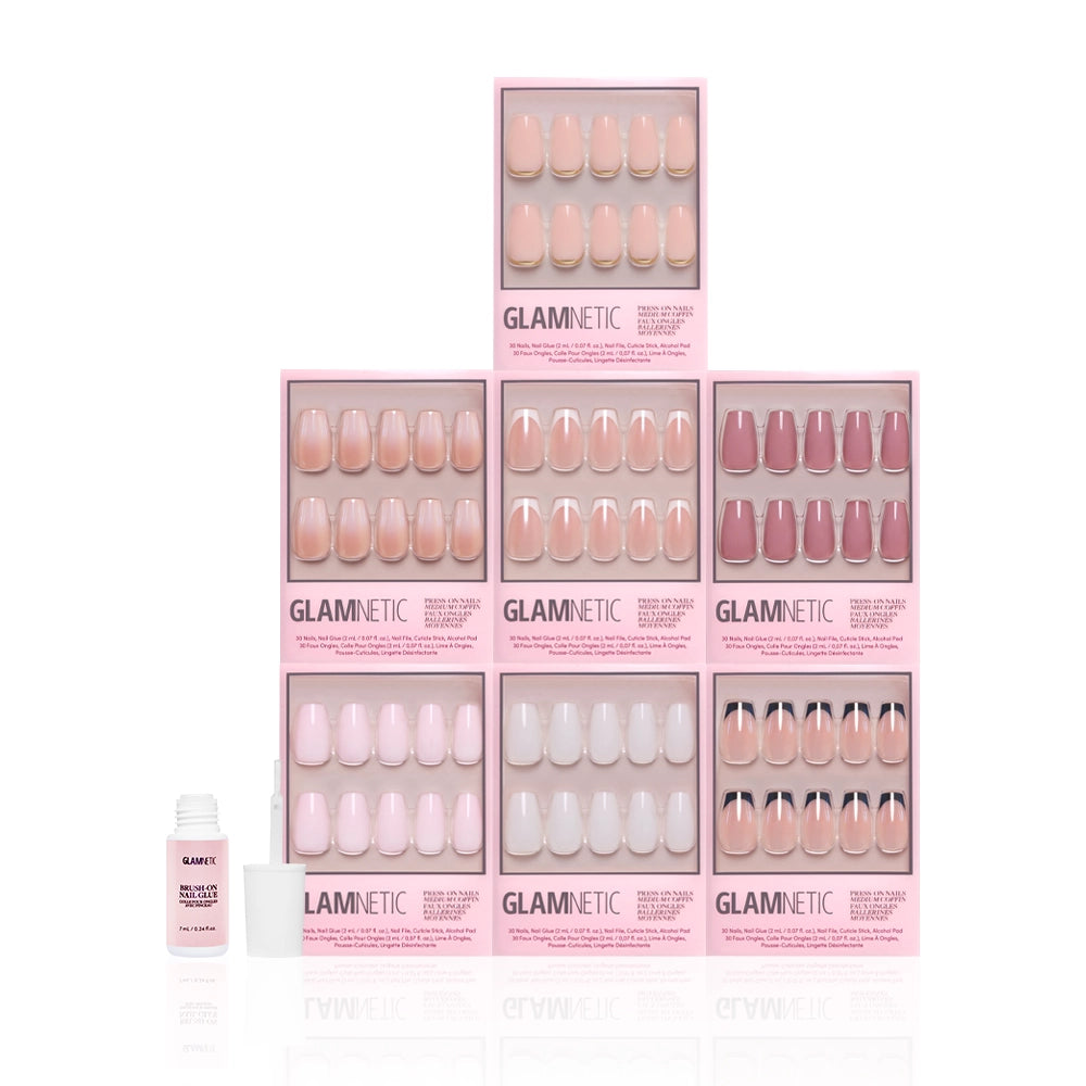 Seven boxes of glamnetic Medium Coffin Icons press-on nails in nude, pink, and mauve shades are stacked with a small white bottle of nail glue in front. Their minimalist designs pop against the clean white background. - Product image
