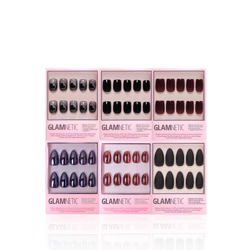 Six sets of glamnetic Meet At Midnight almond press-on nails in pink packaging, featuring black, dark red, and deep purple shades, are displayed in two rows on a white background. - Product image