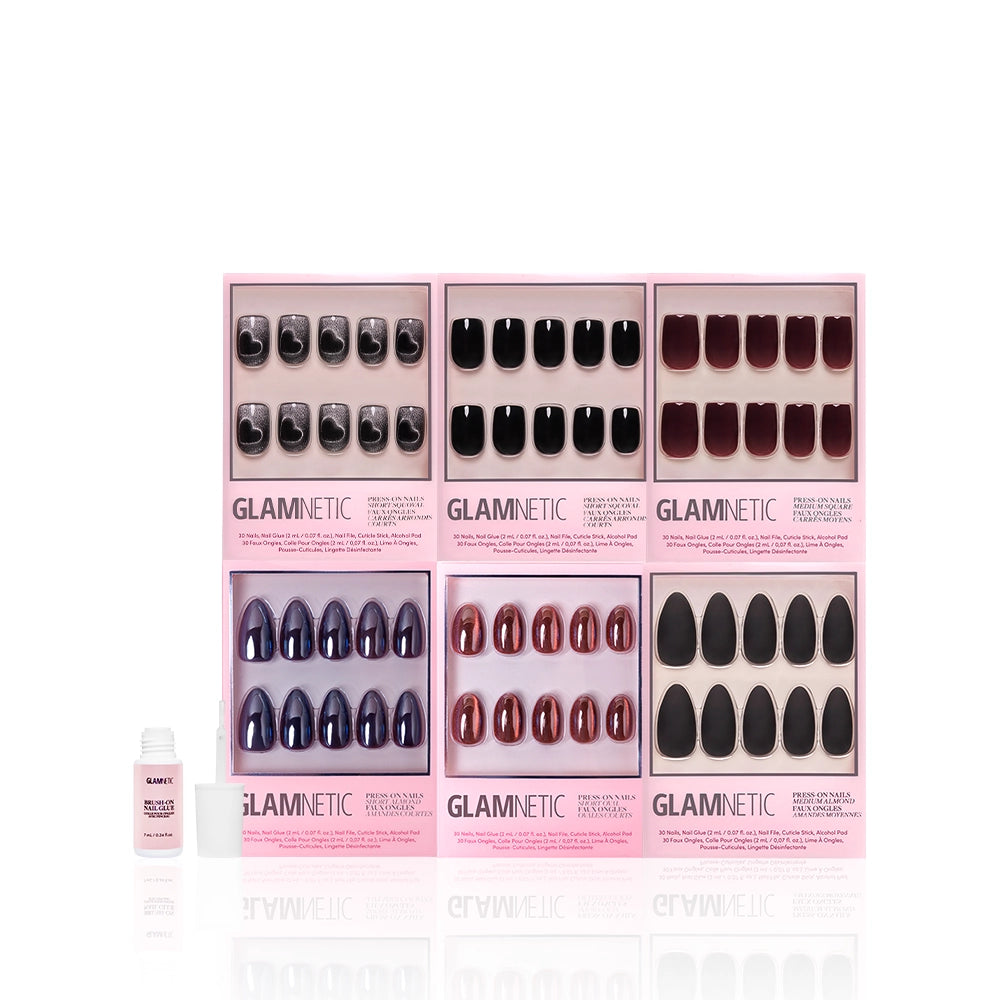 Six glamnetic Meet At Midnight press-on nail sets—featuring almond and black designs—are displayed in pink boxes with a small bottle of nail glue to the left, all arranged on a white background. - Product image