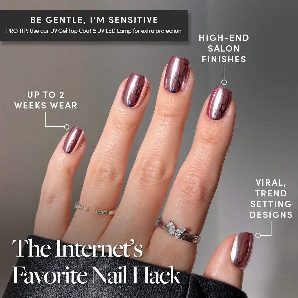 A hand adorned with glamnetic’s Metallic Blush press-on nails—featuring short, squoval shapes and a striking chrome pink finish—is shown wearing rings against a gray background. The text highlights this nail hack for achieving high-end, long-lasting salon results suitable even for sensitive nails. These easy-to-wear Metallic Blush nails merge elegance and durability, making them the perfect choice for those seeking chic, salon-worthy metallic looks at home. - Product image