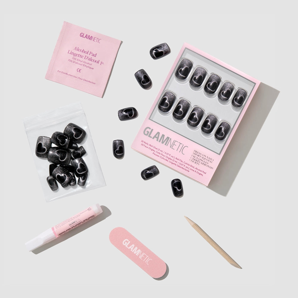 A flat lay of glamnetics Midnight Romance black press-on nails set, featuring a pink nail file, wooden cuticle stick, alcohol pad, glue tube, and extra nails—all neatly arranged on a light background. - Product image