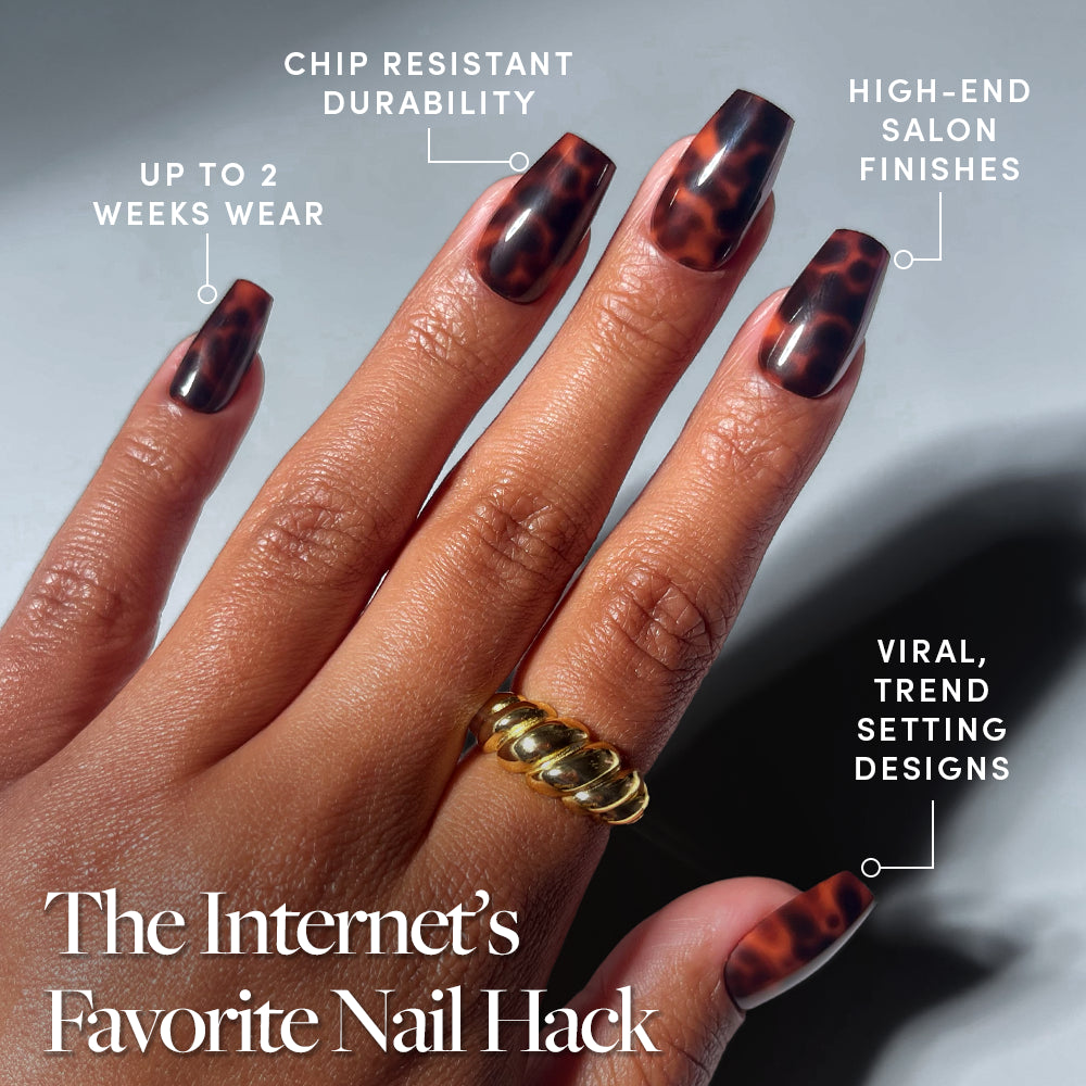 A hand with long, brown tortoiseshell Mine By Right press-on nails by glamnetic in a medium coffin shape, featuring up to 2 weeks wear, chip-resistant durability, salon-quality finish, and viral trend-setting design. Gold twisted ring shown. - Product image
