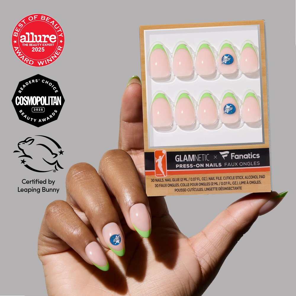 A hand holds a glamnetic Minnesota Lynx Press-On Nail Set box featuring green almond French tips and a sports logo accent; beauty award symbols and the cruelty-free Leaping Bunny certification appear nearby.