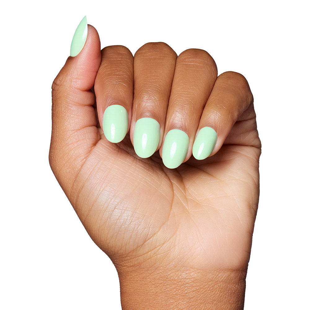 A hand with medium brown skin shows short, oval nails painted in glamnetic’s Mint Green—a glossy, pastel mint shade—against a white background. - Product image