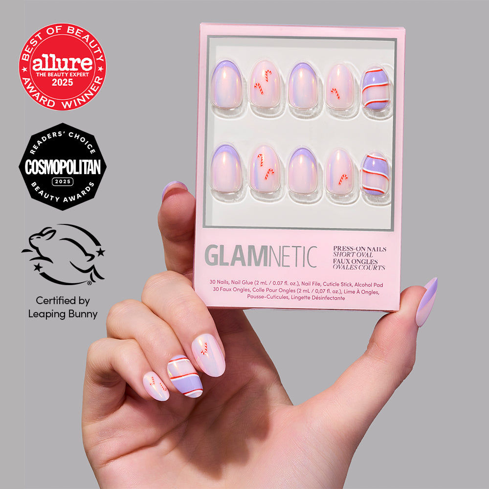 A hand with pastel and striped Glamnetic Miss Minty Press-On Nails in a chic short almond shape holds a box of Glamnetic nails. Allure and Cosmopolitan award badges along with a Leaping Bunny certification logo appear on the left, offering perfect inspiration for your next holiday manicure. - Product image