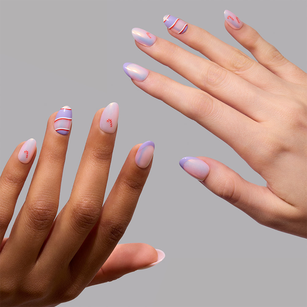 Two hands with manicured nails in soft pastel shades showcase minimalist nail art, featuring wavy red and blue lines on select nails, set against a plain gray background. The chic “Miss Minty” press-on nails by glamnetic are styled in a modern short almond shape—perfect for the holidays. - Product image