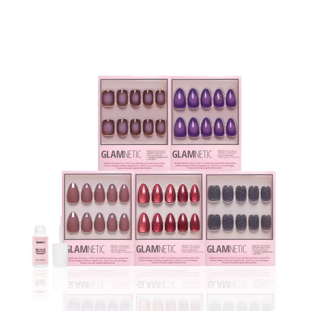 Five boxes from the glamnetic Moon Child Collection press-on nail sets in various colors—nude, red, purple, gray, and glitter—are arranged in two rows with a small bottle of nail glue on the left against a white background. These stylish short almond nails from the Moon Child Collection by glamnetic provide a chic and effortless manicure for any occasion. - Product image