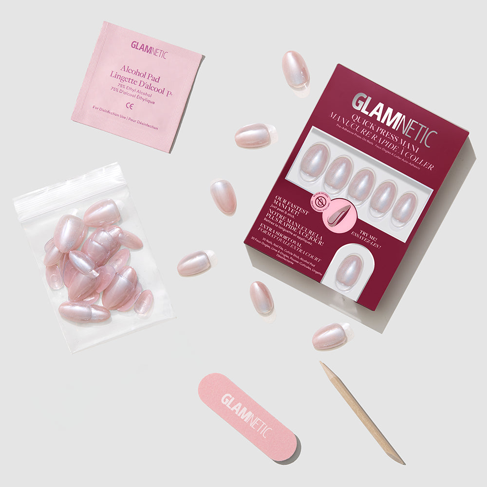 A set of glamnetic Nude Glazed press-on nails, featuring a maroon box, pink stick-on nails, nail file, cuticle stick, glue tube, alcohol pad, and extra nails arranged on a light background. - Product image