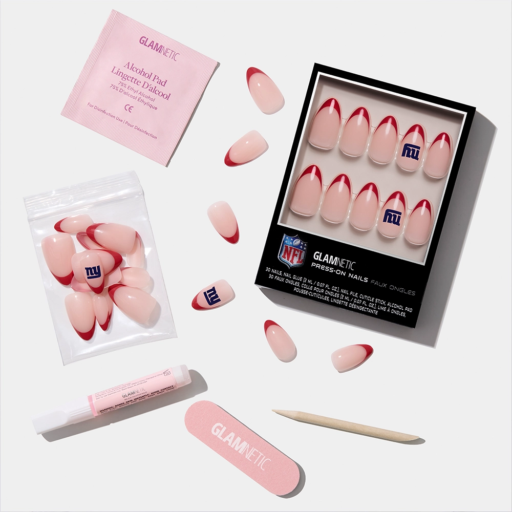 The glamnetic New York Giants Press-On Nail Set features pink and red nails, some with the team logo, and includes an alcohol pad, glue tube, nail file, and wooden cuticle stick. - Product image