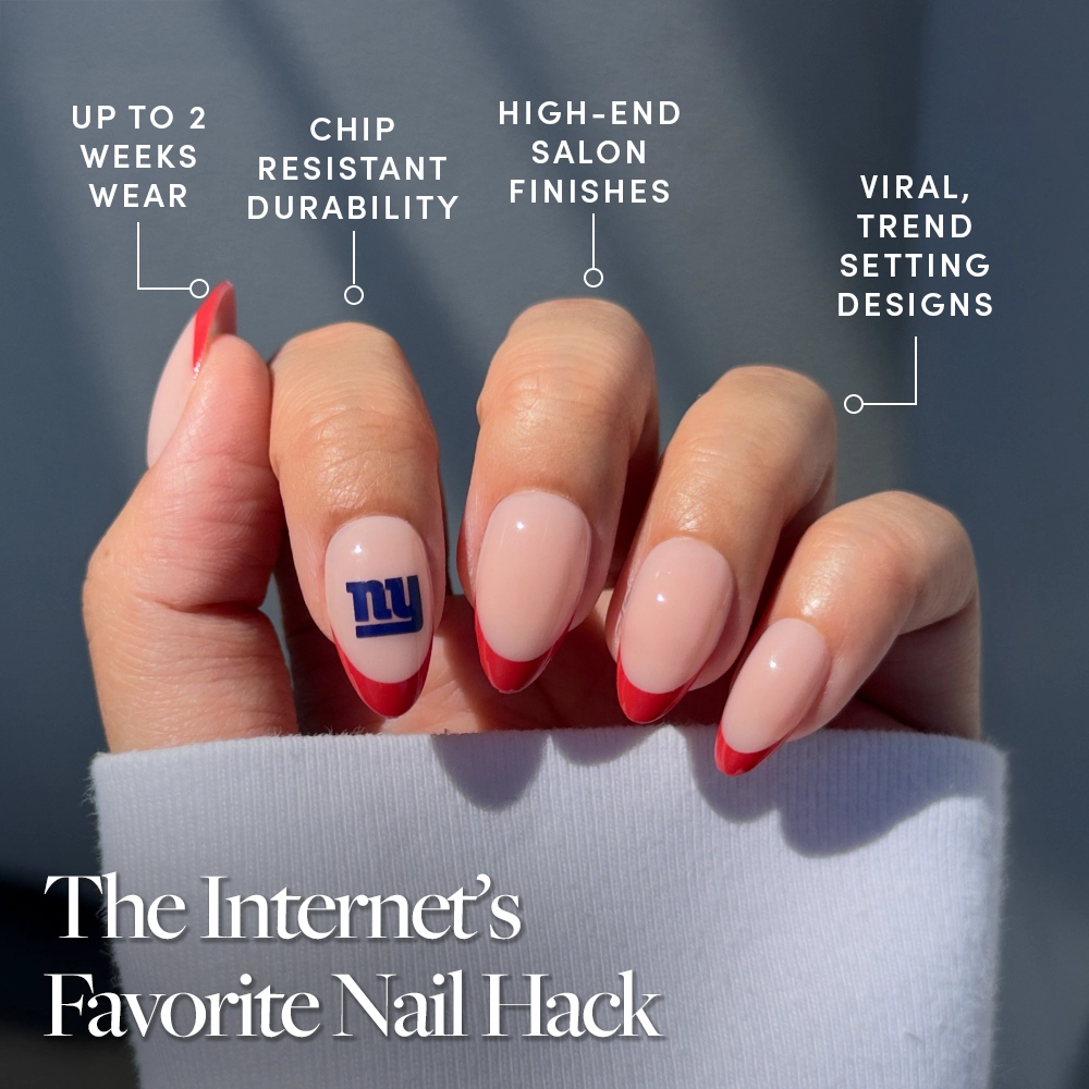A hand with manicured nails featuring red French tips and the New York Giants logo using the glamnetic New York Giants Press-On Nail Set. Enjoy up to 2 weeks wear, chip-resistant salon finishes, and trendy designs—perfect for NFL nail art fans. - Product image