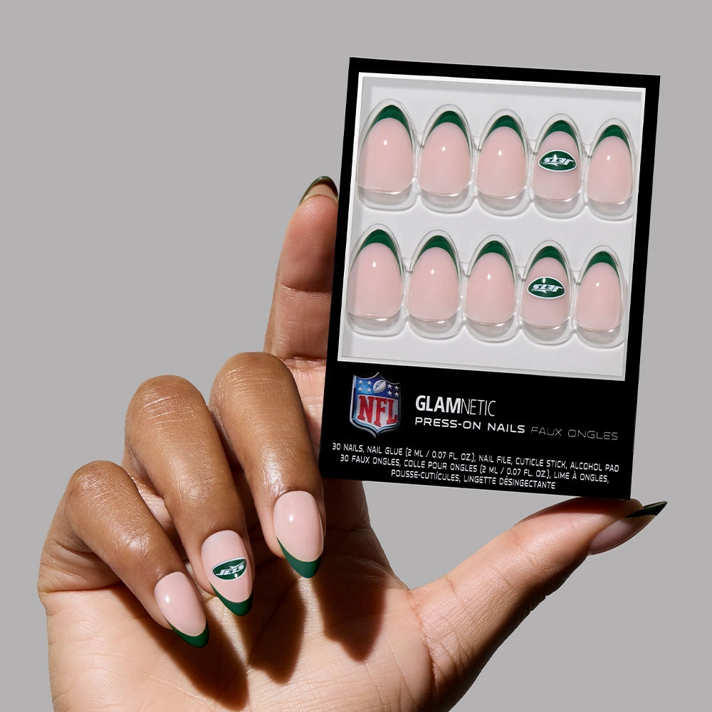 A hand with almond French tip nails holds a glamnetic New York Jets Press-On Nail Set, featuring matching designs and an accent nail with the Jets logo.