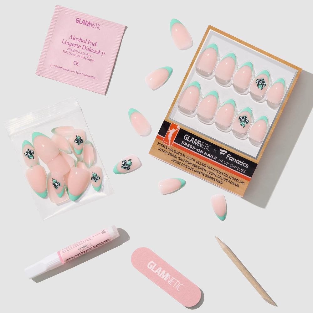 The glamnetic New York Liberty Press-On Nail Set features French tips with a pale pink base and teal tips, some with stars. It includes a nail file, cuticle stick, alcohol pad, glue, extra nails, and packaging—displayed on a light surface. - Product image