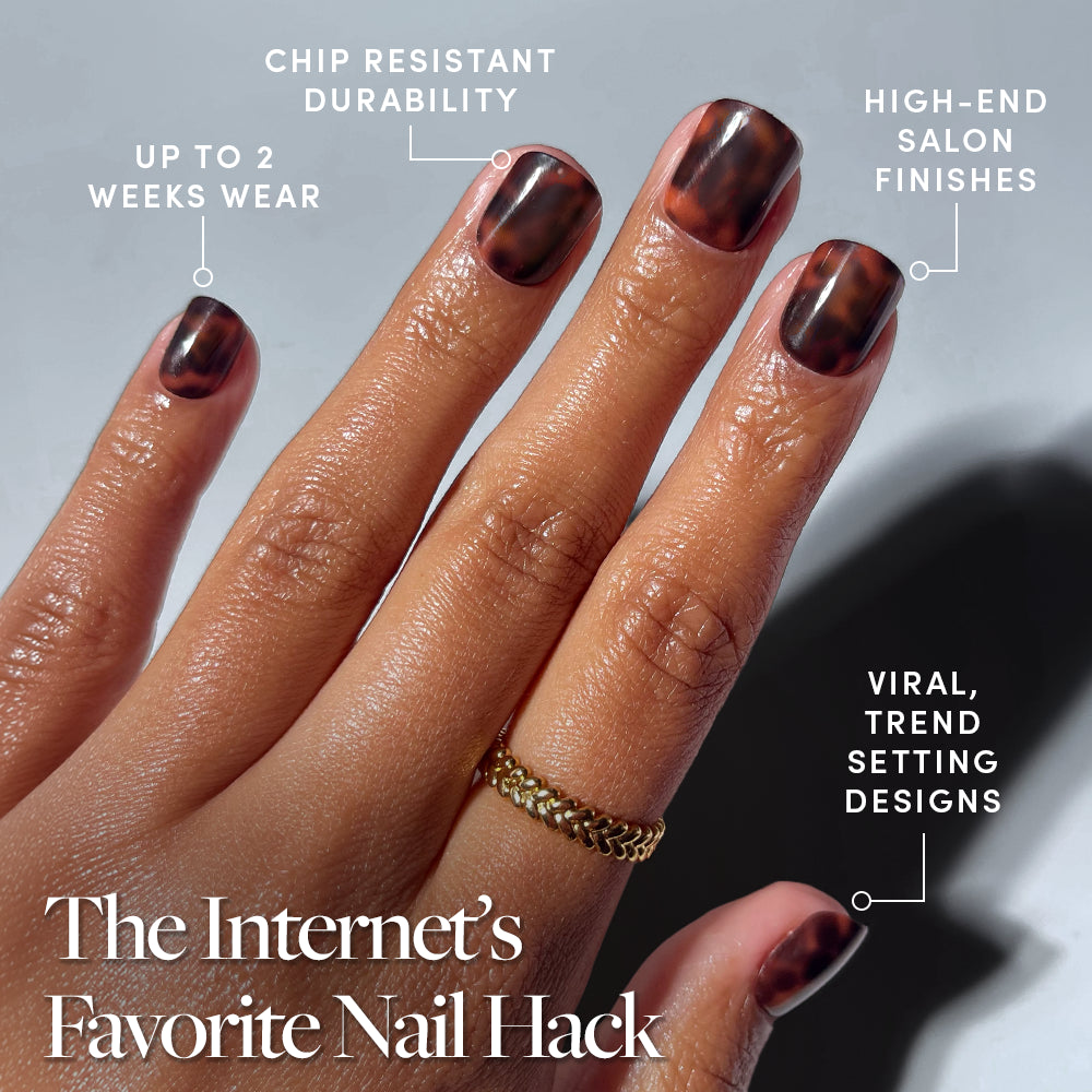 A hand with glossy, medium oval Own It All tortoiseshell French tip nails by glamnetic shows off up to 2 weeks of chip-resistant wear, salon-quality finish, and trending design. Gold chain ring on middle finger. Perfect press-ons for trendsetters. - Product image