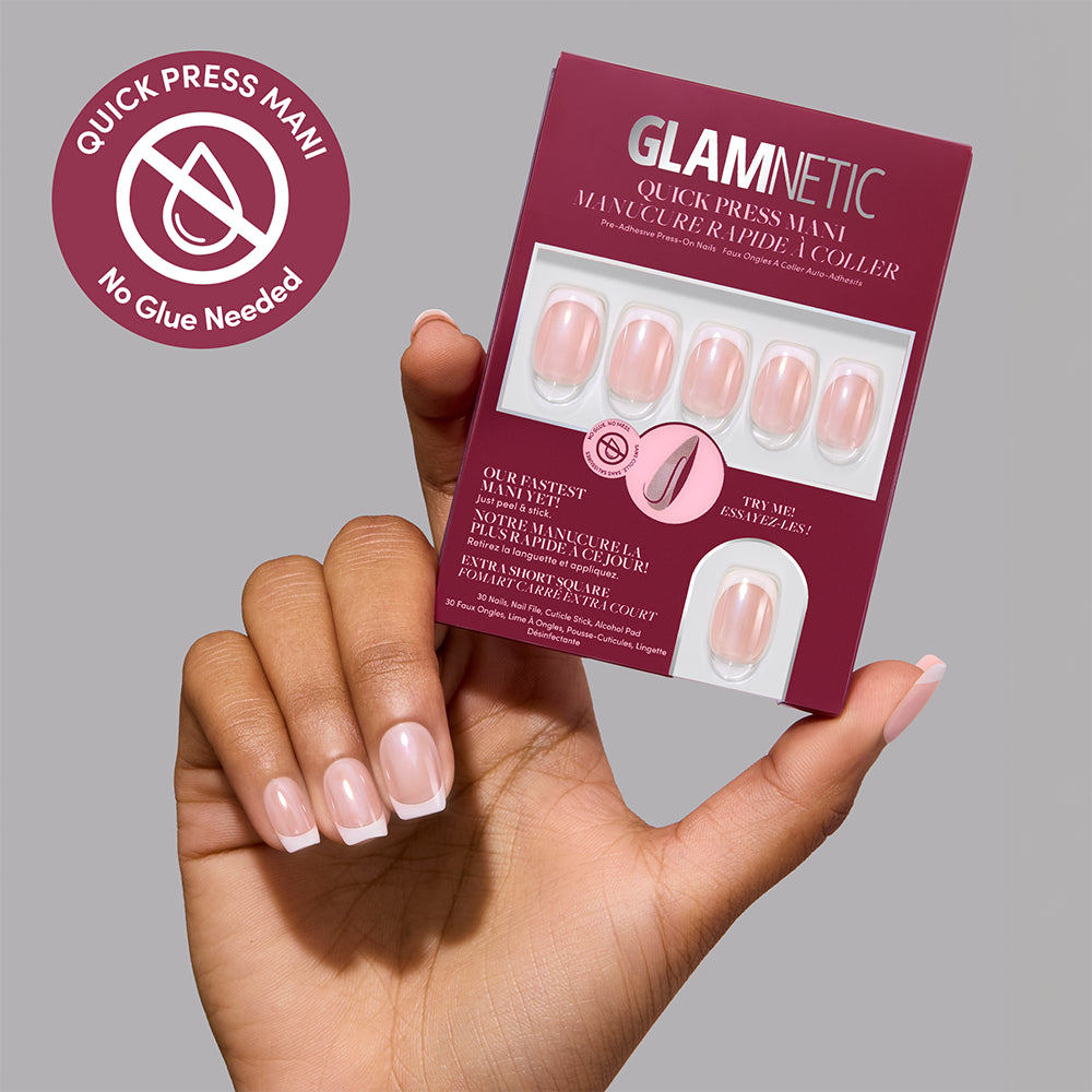A hand with a French manicure holds a box of Glamnetic Pearl Du Jour quick press nails, which features a display window and product information. - Product image