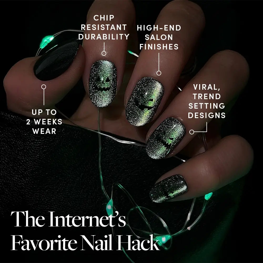 A hand with black and glittery green ombré glamnetic Peek-o’-Lantern press-on nails holds glowing green string lights. Text emphasizes their durable, salon-quality finish, trendy designs—including options for short round velvet shimmer nails—and up to two weeks of wear. Caption: The Internet’s Favorite Nail Hack. - Product image