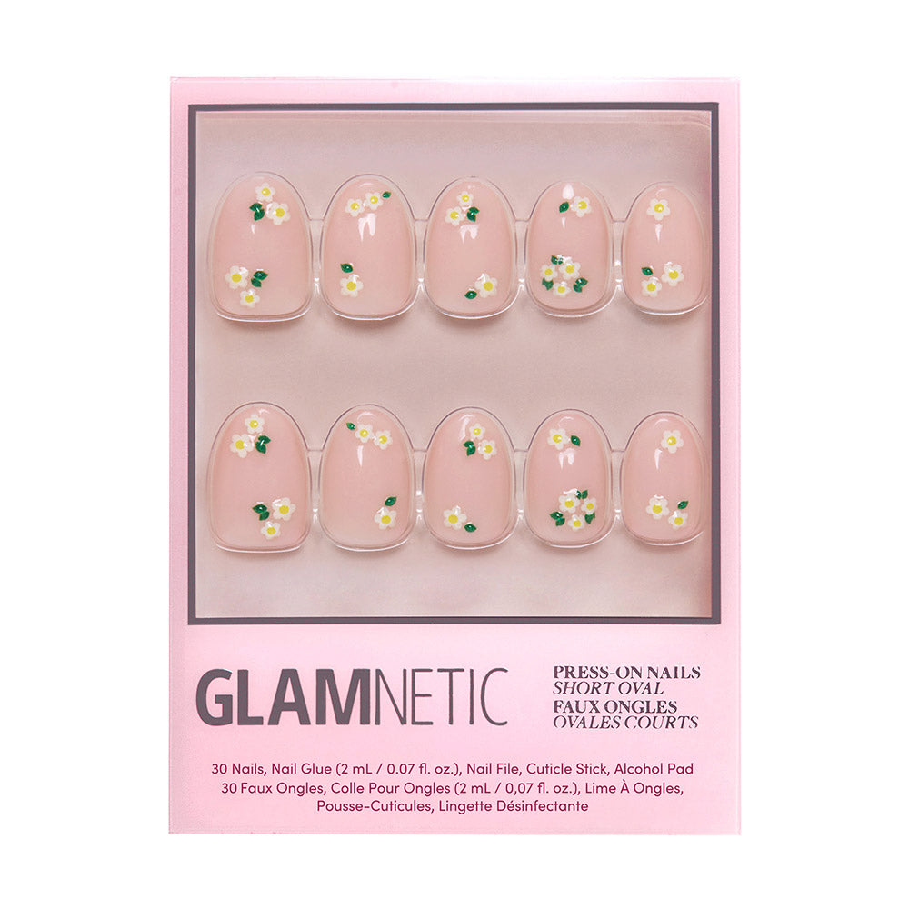 A box of glamnetic Petals nails in short oval shape with a clear pink base, glossy finish, and white and yellow daisy accents. The pink packaging displays the nails in two rows.