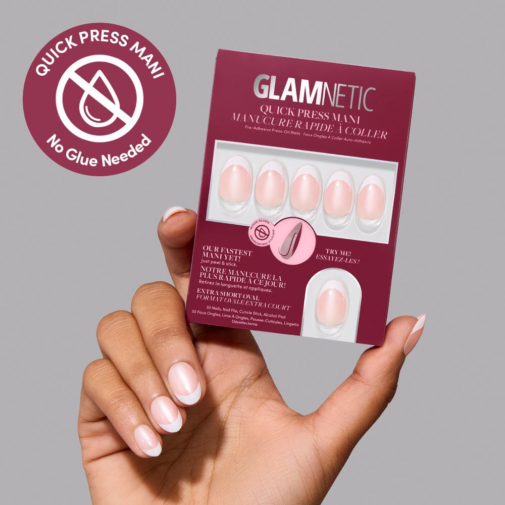 A hand holds a box of Glamnetic Petite Pearls, which are extra short almond press-on nails featuring a glazed French manicure design. - Product image