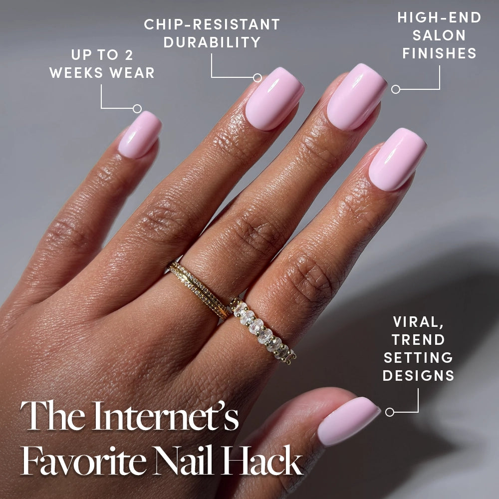 A hand displays glamnetic's Pink Control nails in a short squoval shape with a glossy blush finish. Benefits shown: up to 2 weeks' wear, chip-resistant durability, salon-quality look, and trend-setting style. Two gold rings accent the middle finger. - Product image