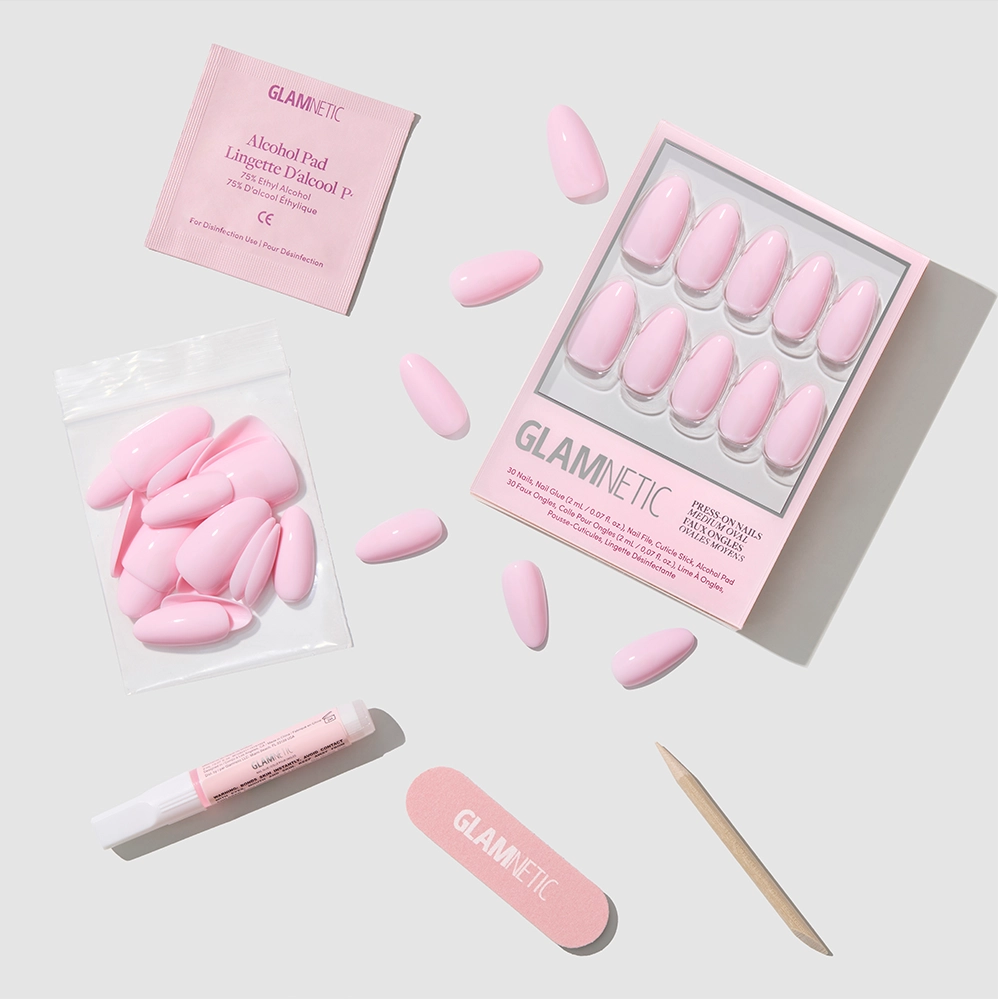 A flat lay of glamnetic’s Pink Obsession kit, featuring medium oval pink press-on nails, glue, nail file, cuticle stick, alcohol pad, and extra nails—all arranged neatly on a light background.